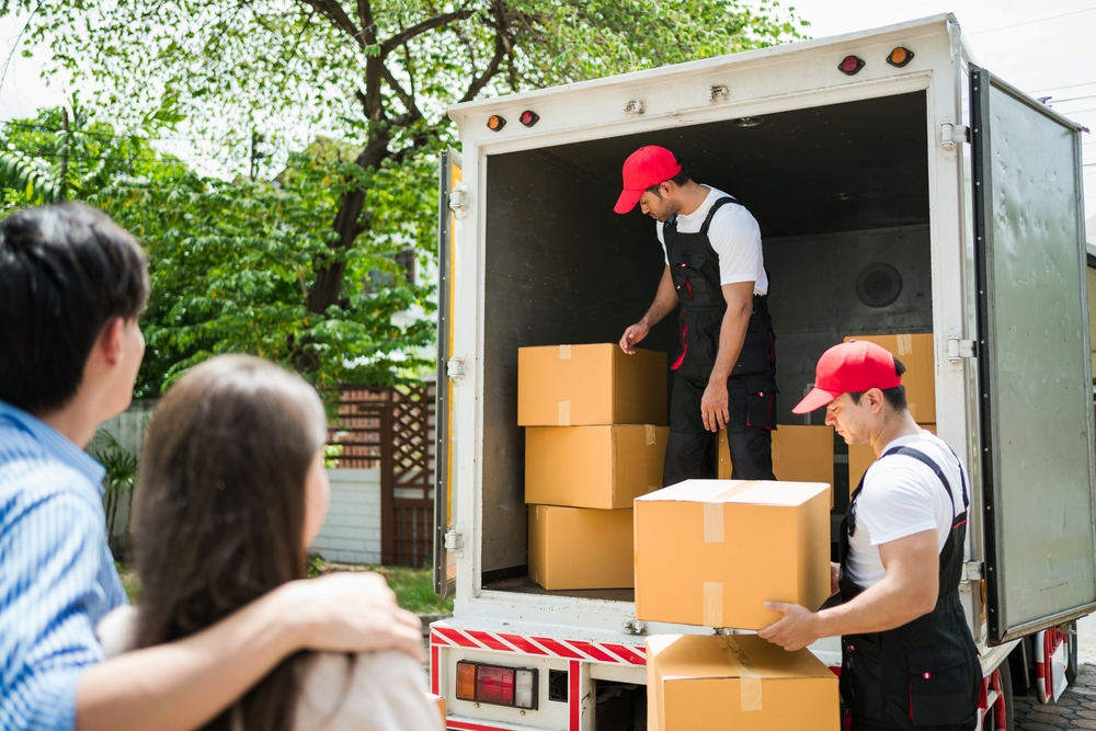 Asian,And,Caucasian,Workers,In,Uniform,Unloading,Cardboard,Boxes,From